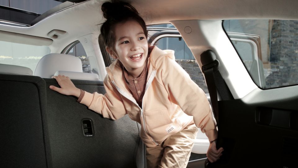 Dívka nastupuje na zadní sedadla nového sedmimístného SUV Hyundai SANTA FE Hybrid.